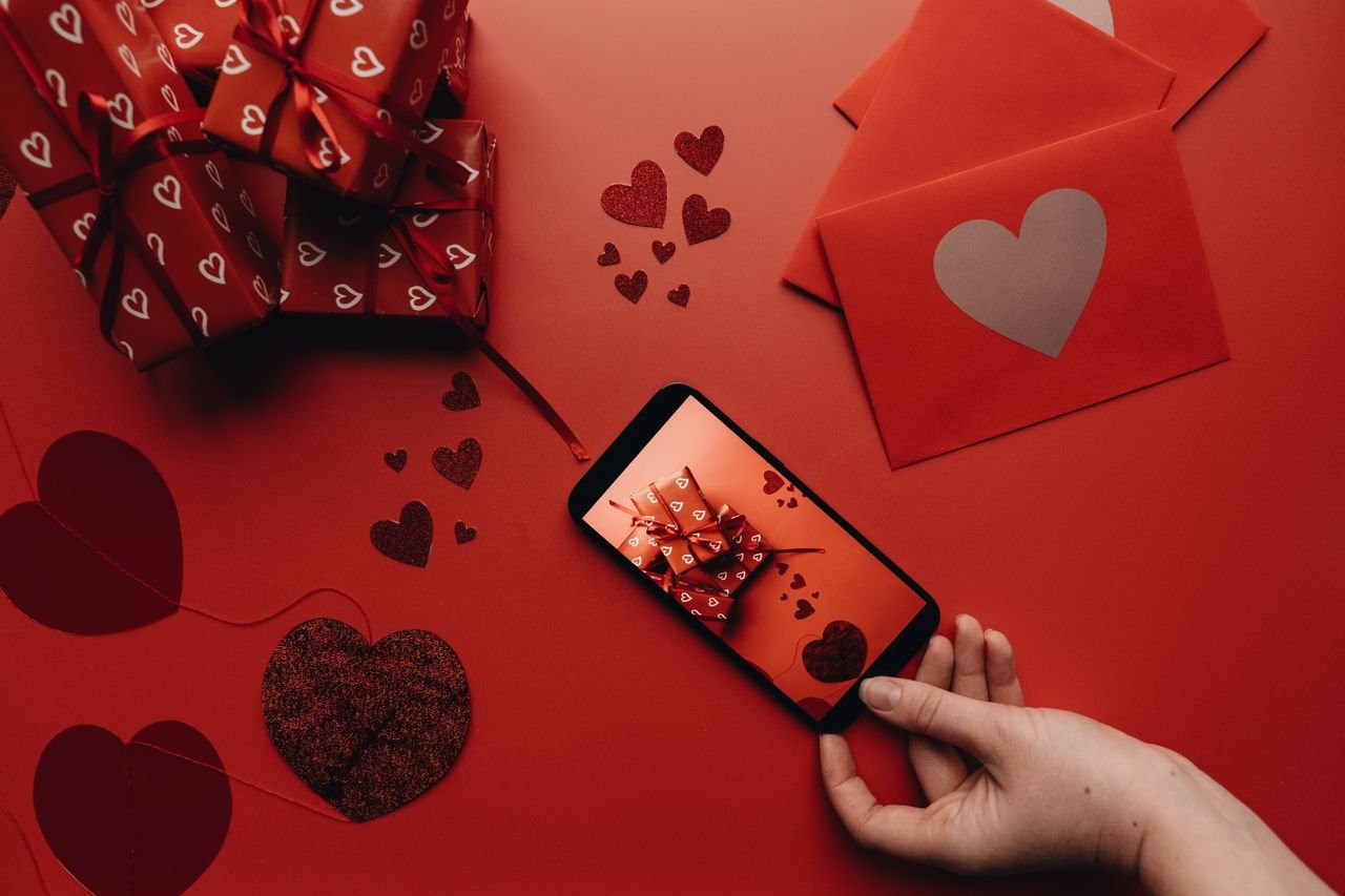 Crafting Captivating Headlines: Your awesome post title goes here Romantic Valentine's Day scene featuring heart-themed gifts and a smartphone on a red background.